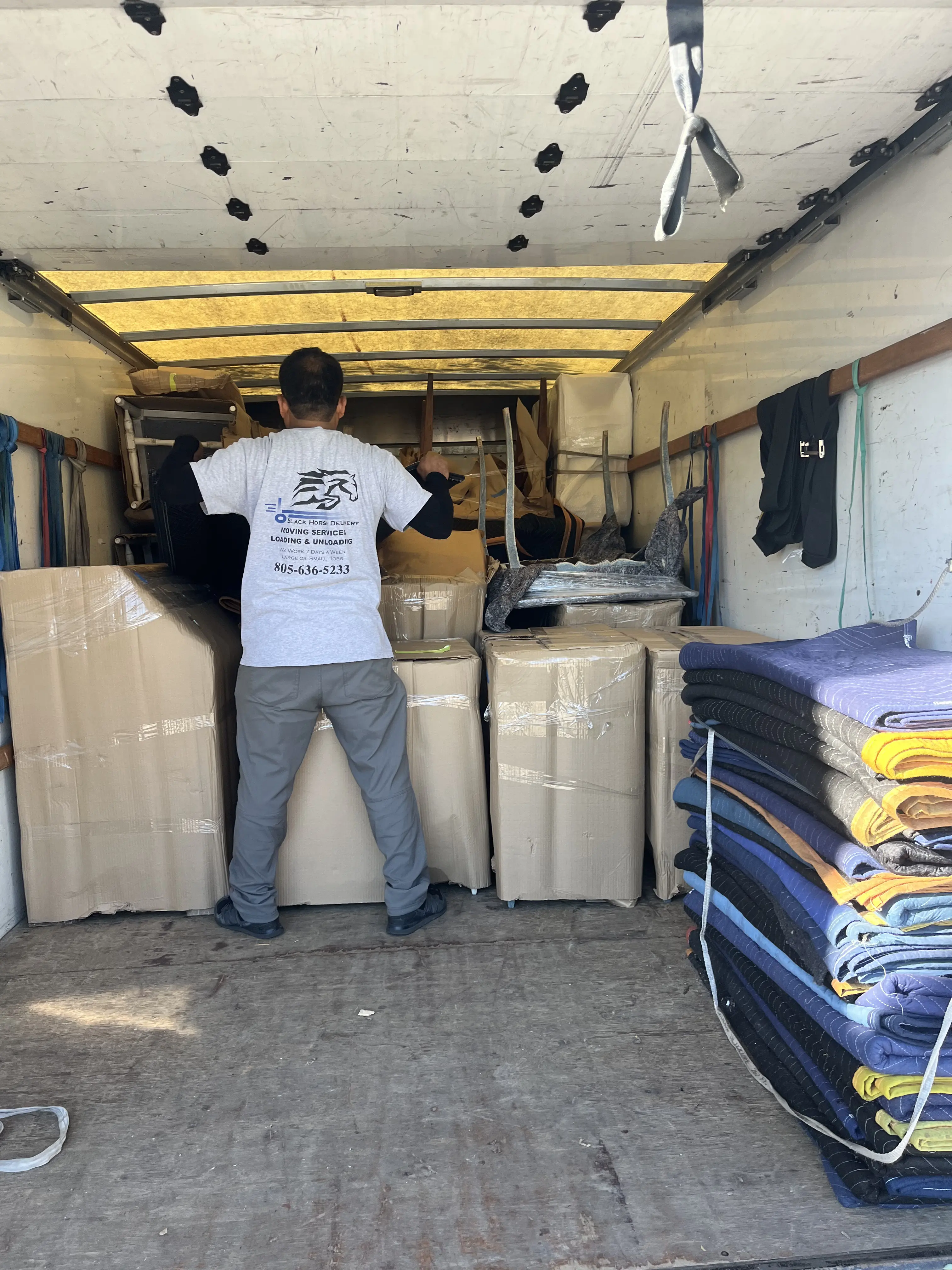 Black Horse Delivery mover loading boxes and furniture into a moving truck